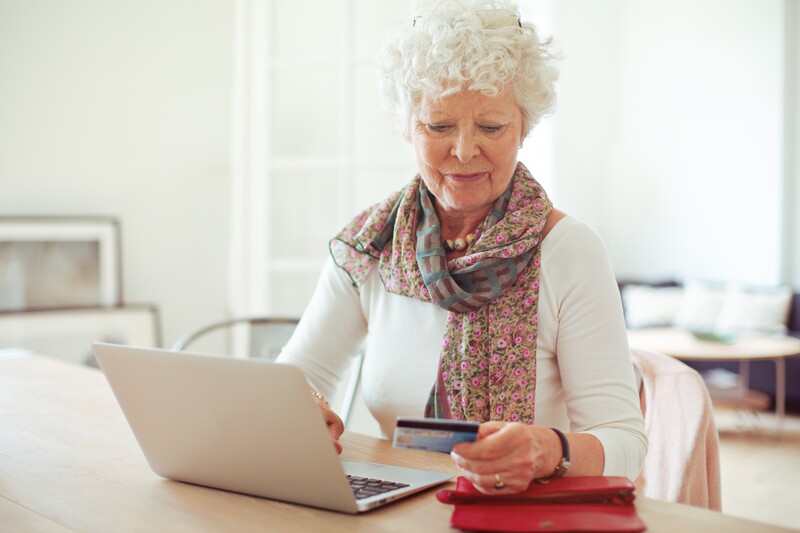 senior woman entering credit card information to do online shopping