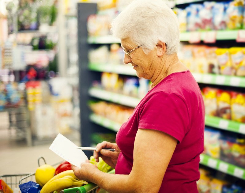 elderly woman shopping for groceries with a list of nutritious foods